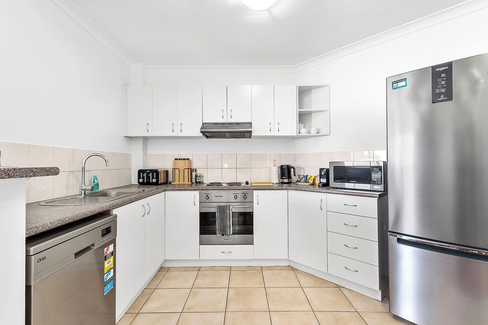 Cook in a bright, modern kitchen with white cabinets, stainless steel appliances, and ample counter space for easy meal prep.