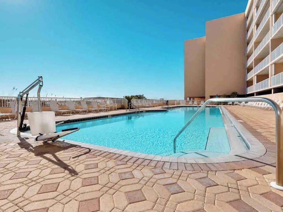 Take a refreshing dip in the sparkling pool, complete with accessibility features and poolside lounging area under sunny skies.