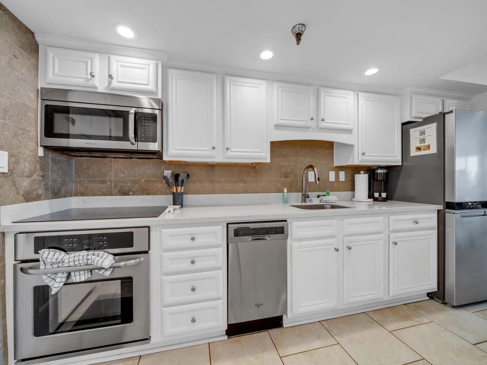 Your fully equipped kitchen awaits with gleaming stainless steel appliances and pristine white cabinets, perfect for preparing meals.