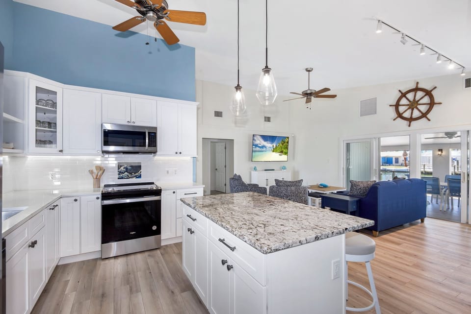 Open concept modern kitchen with quartz countertops, tile back splash, and all new stainless steel appliances