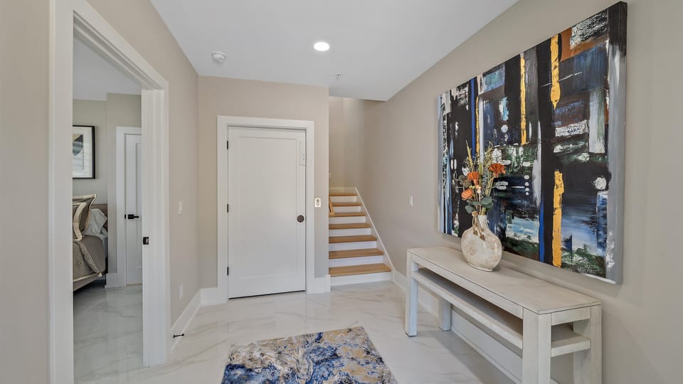 Step into a beautifully styled entryway with a grand art piece, leading to the main living areas and a convenient staircase to the upper levels.