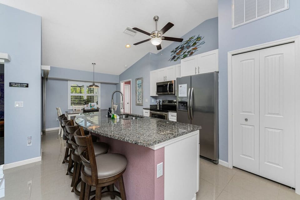 Spacious kitchen with granite countertops, stainless steel appliances, a garbage disposal, and a pantry for storing groceries and essentials, plus a large island with seating for four guests perfect for casual dining or gathering while meals are prepared.