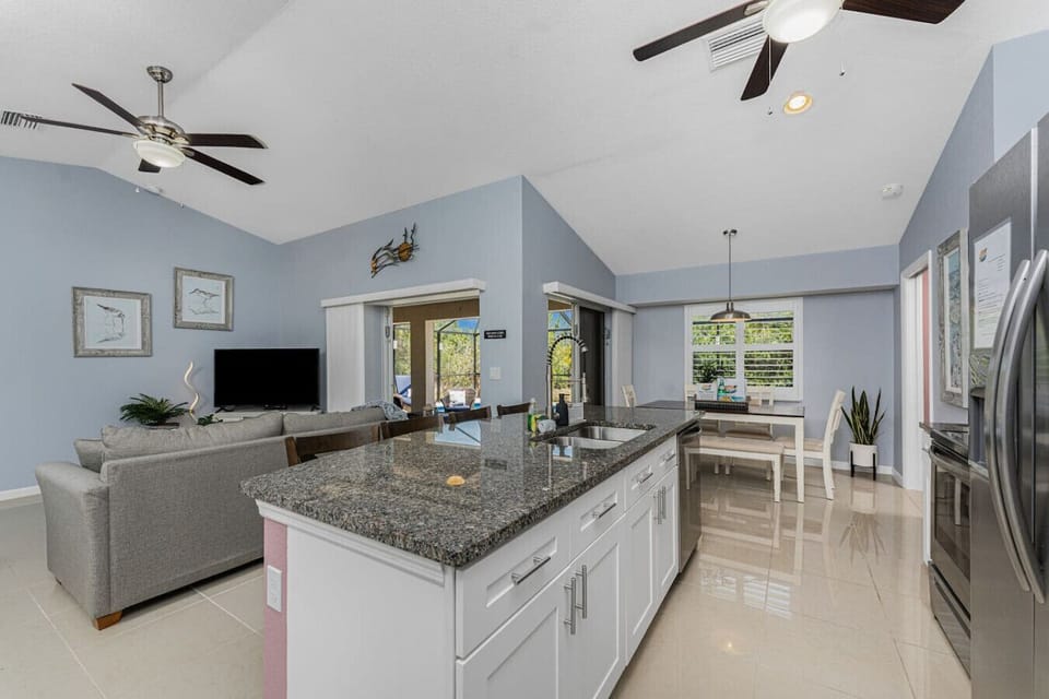 Open kitchen with granite countertops, stainless steel appliances, and a spacious island overlooking the living and dining areas, creating a perfect space for gathering and entertaining.