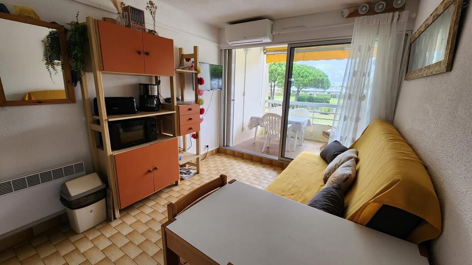 Bright living room with sofa bed for two people, TV and views of the terrace and green areas