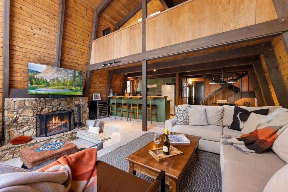 Spacious living room opening to `the pit`, dining area and kitchen with floor to ceiling windows, wood burning fireplace and smart TV.