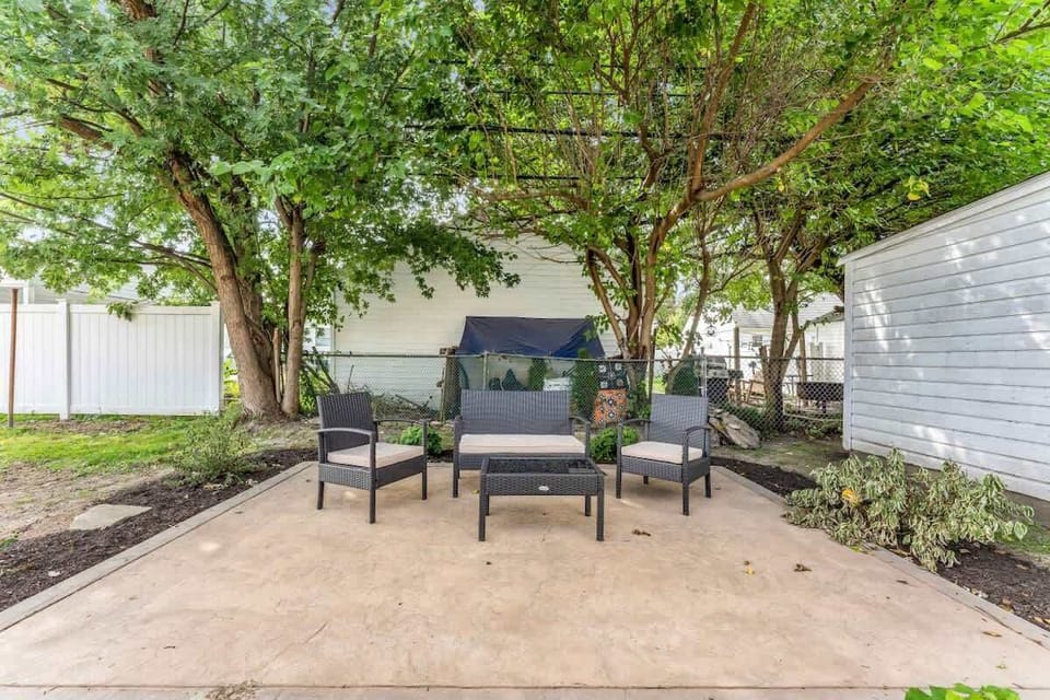 Shaded backyard patio w/ comfy seating, perfect for relaxing under the trees