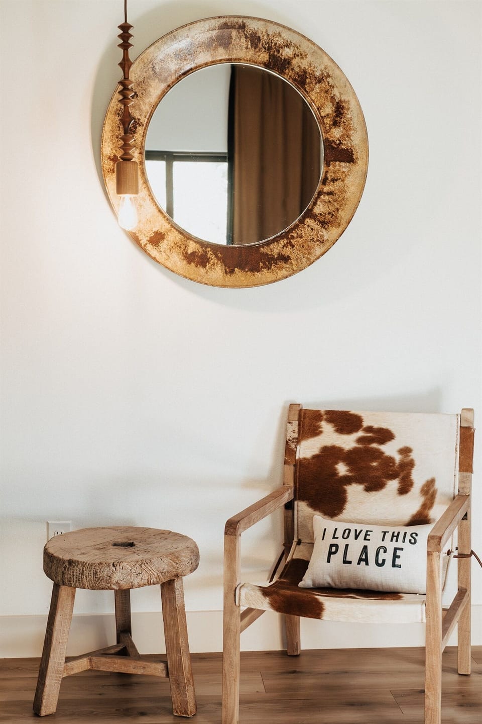 A welcome corner inside the Lazy Spur Suite — a leather chair, a wooden stool, and a handcrafted welcome pillow at Gaines Ranch on the Square.