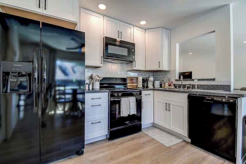 A stylish, fully equipped kitchen with black appliances, white cabinetry, and a sleek subway tile backsplash—perfect for cooking up delicious meals. #ModernKitchen