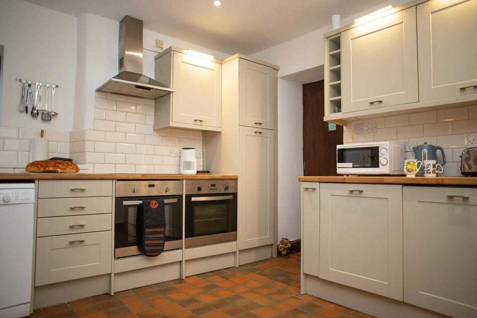 Cream kitchen with white tiled splashback, double oven and extractor hood