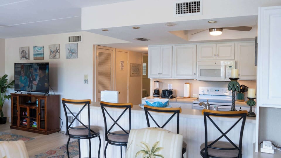 Bright and open kitchen with bar seating flows into the cozy living area. Fully equipped with modern appliances and plenty of counter space, it’s perfect for cooking, dining, or gathering with family while enjoying the inviting coastal décor.
