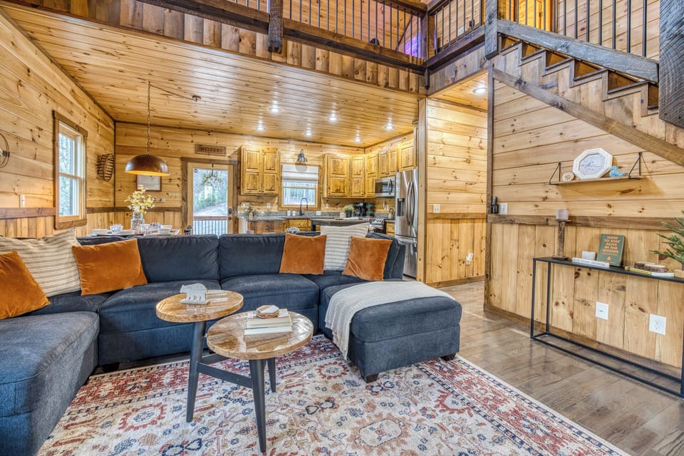 Relax in a cozy living space w/ plush seating, warm wood, rug & coffee tables.