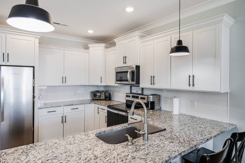 Spacious kitchen counter perfect for meal preparation, equipped with an oven, microwave, stove with oven, and a single-serve coffee maker.