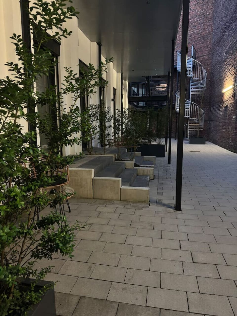 Grüne Oase im urbanen Innenhof: Stilvolle Apartments mit modernem Zugang, umgeben von Pflanzen und industriellem Charme – perfekt für einen entspannten Rückzugsort mitten in der Stadt.