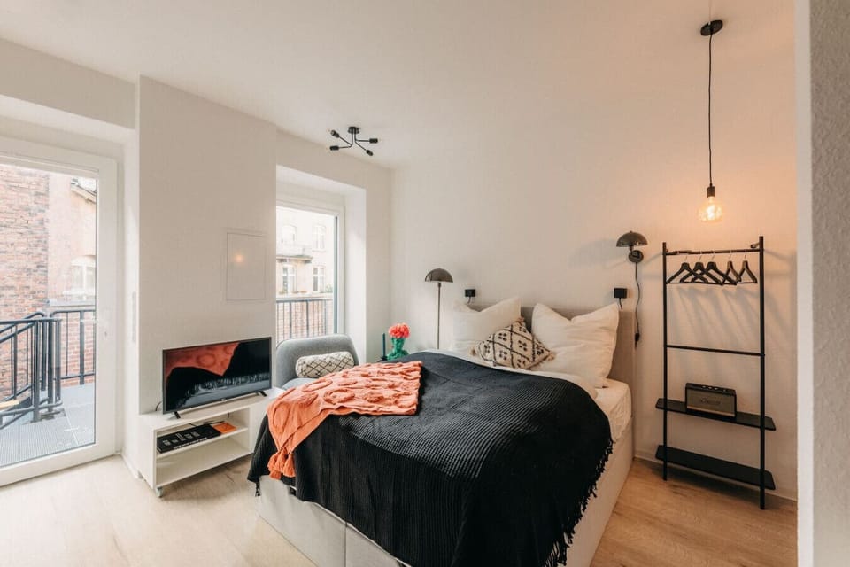 Dieses stilvolle Apartment vereint modernes Design mit Gemütlichkeit. Warme Farben, weiche Textilien und sanftes Licht schaffen eine einladende Atmosphäre. Genieße entspannte Abende im komfortablen Bett oder auf dem Balkon mit Blick in den Innenhof!