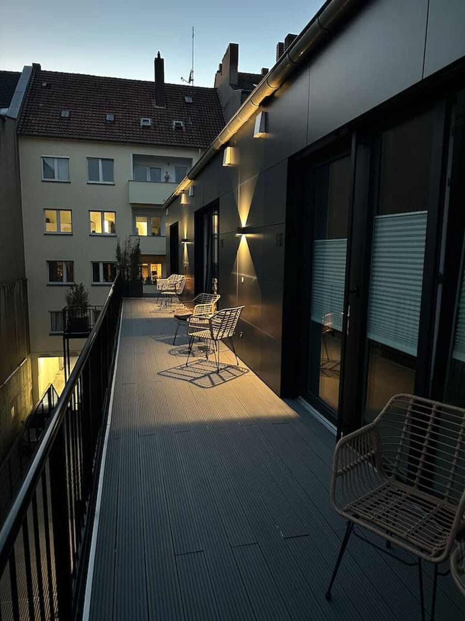Der perfekte Ort, um den Abend ausklingen zu lassen – stilvolle Balkonmöbel, sanfte Beleuchtung und ein Blick auf die umliegenden Stadthäuser schaffen eine einladende Atmosphäre.