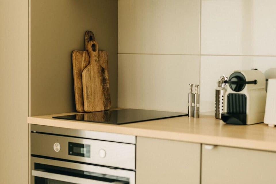 Kochen mit Stil – diese moderne Küche verbindet Funktionalität mit warmen, natürlichen Akzenten. Mit hochwertigen Holzbrettern, einer stilvollen Espressomaschine und edlen Gewürzmühlen wird jede Mahlzeit zum Genussmoment.