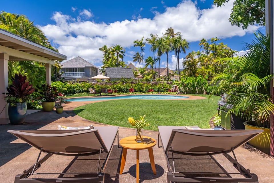 Relax and unwind in the pool, surrounded by lush tropical plants and vibrant flowers for a serene retreat.