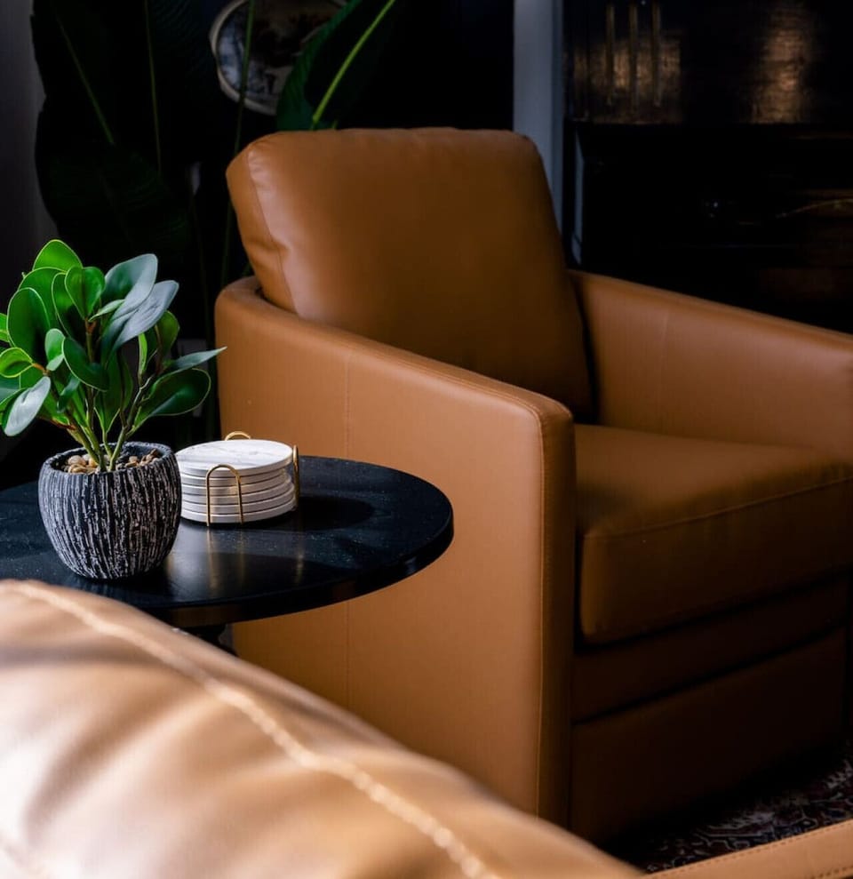 ✨ Our cozy lounge area offers the perfect blend of modern elegance and comfort, featuring leather seating, sleek black accents, and a touch of greenery to set the mood.