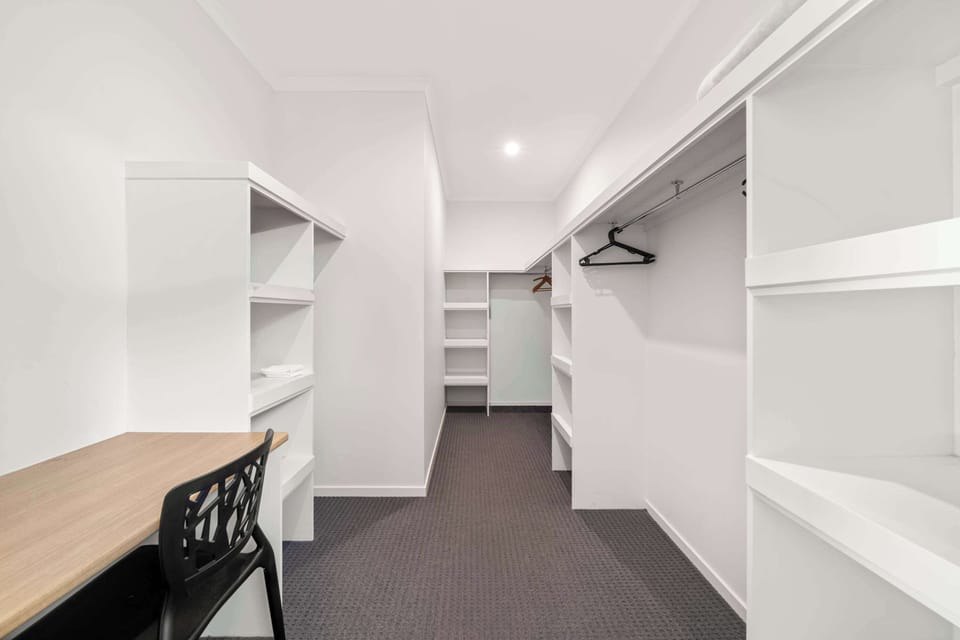 Primary bedroom featuring a queen bed and walk in wardrobe.