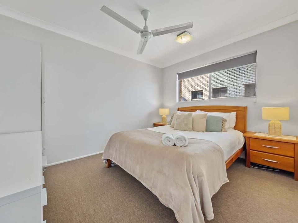 Rest easy in the spacious first bedroom featuring a comfortable queen bed and a ceiling fan.