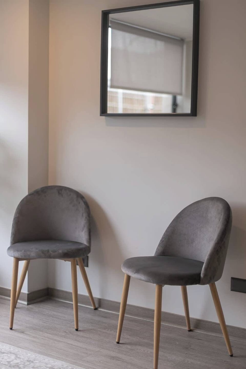A cozy corner with stylish gray chairs and a mirror, perfect for relaxation or a quiet moment.