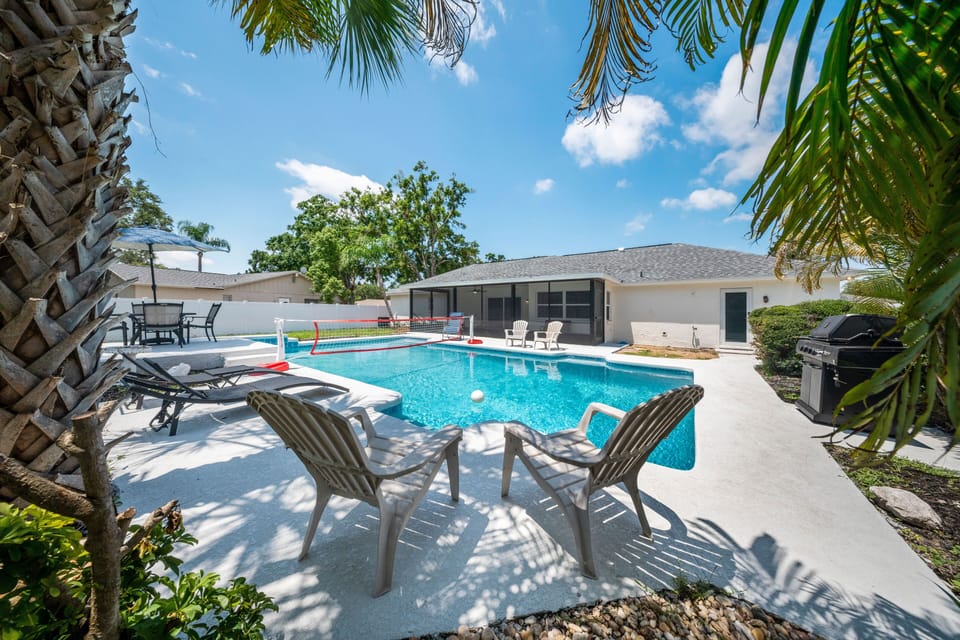 Enjoy a spacious backyard with a large pool and volleyball net with lounging.