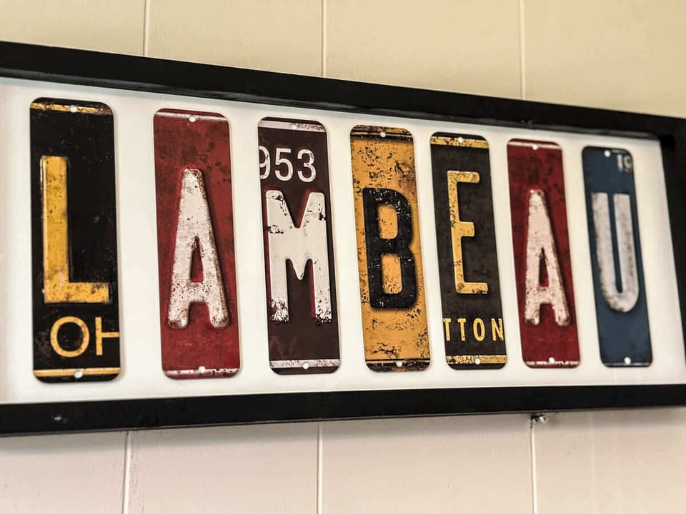 A unique shot of artwork spelling "Lambeau" crafted from colorful license plates, adding a fun and local touch to the space. This eye-catching piece celebrates the iconic Lambeau Field, offering a perfect blend of style and Green Bay pride.