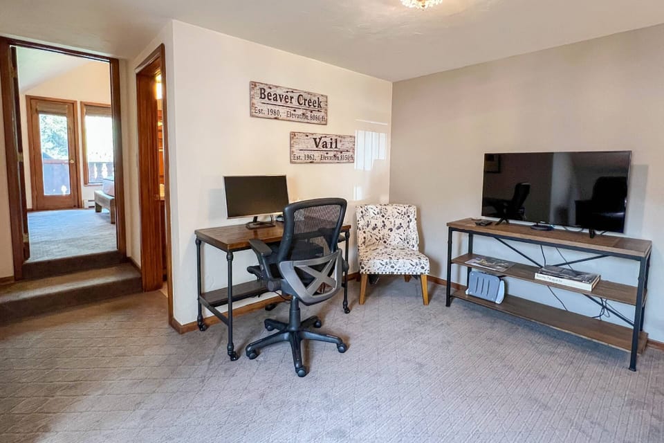 Enjoy a dedicated workstation, a TV for downtime, and two cozy club chairs for comfort.