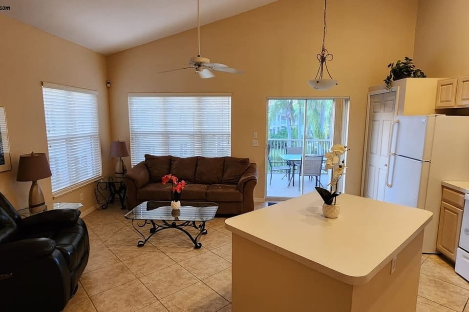 Bright open-concept living space with vaulted ceilings, cozy seating, and direct access to the private screened balcony.