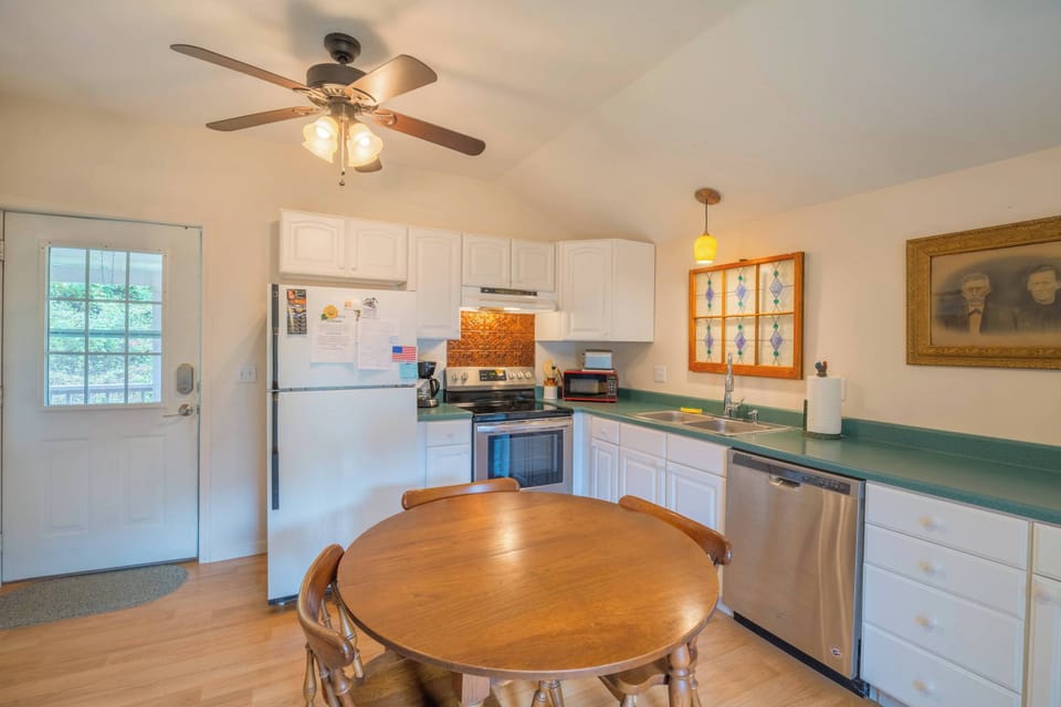 Enjoy cooking in this polished kitchen highlighting deep green counters and professional stainless steel appliances. The simple white walls and ample storage offer a fresh and inviting atmosphere.