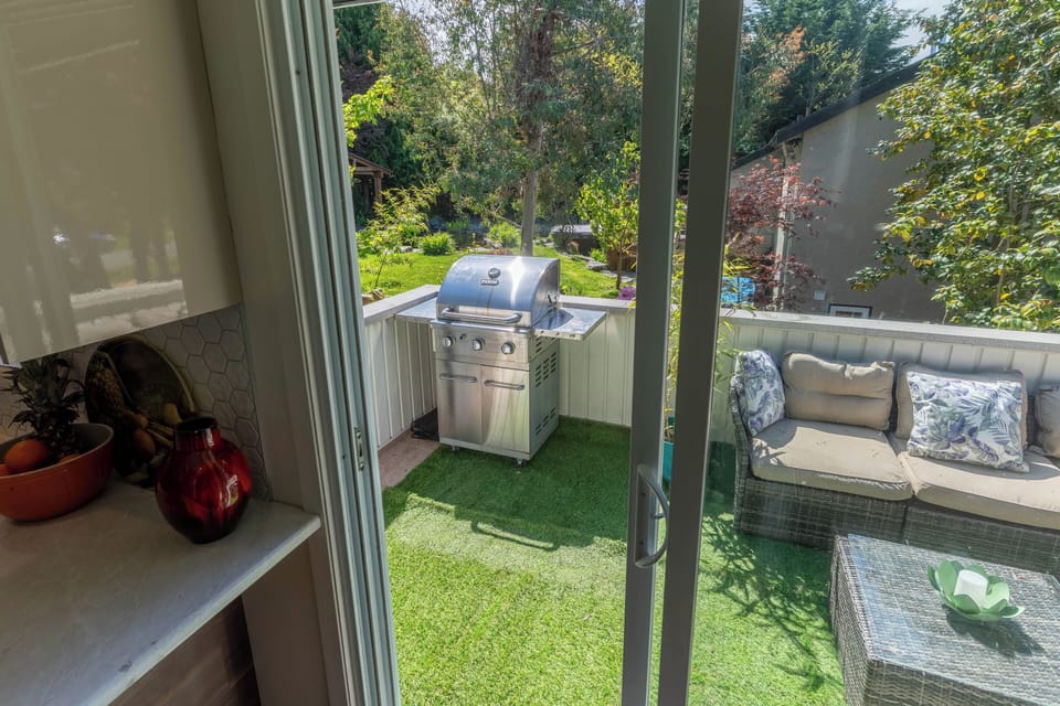 Sunny patio with BBQ, seating with garden and park views.