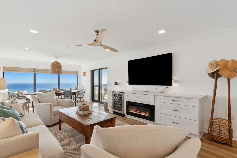 Luxury Living Area Featuring Plush Couch and Chairs, Flat Screen Smart TV, and Modern Coastal Decor