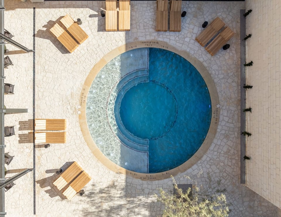 Dive into a sunlit pool oasis with serene seating.