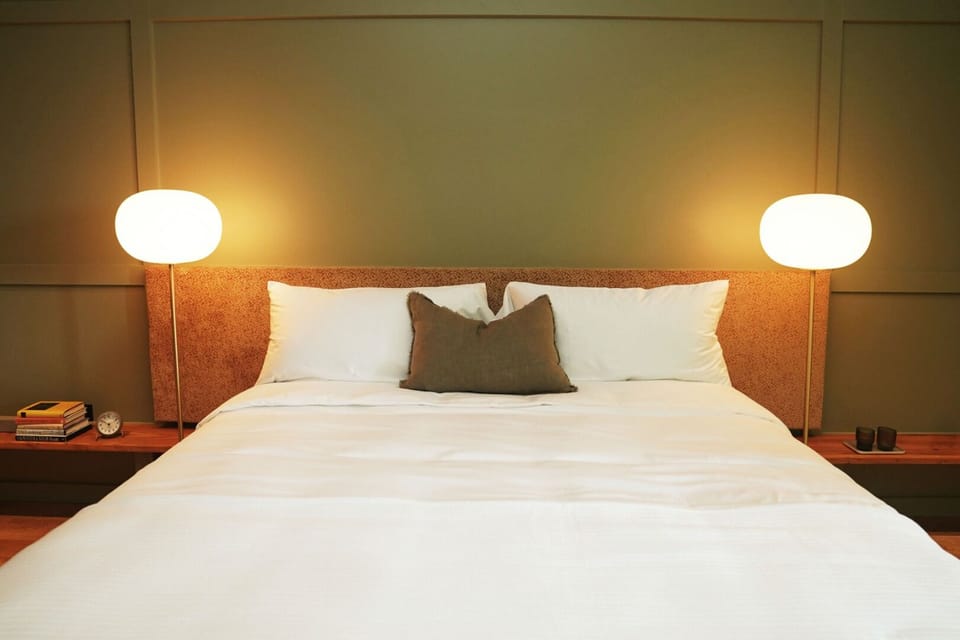 Sink into crisp linens under warm, calming bedside glow.