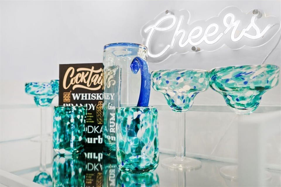 Fun cocktail station with glassware and a “Cheers” neon sign for your happy hour moments.