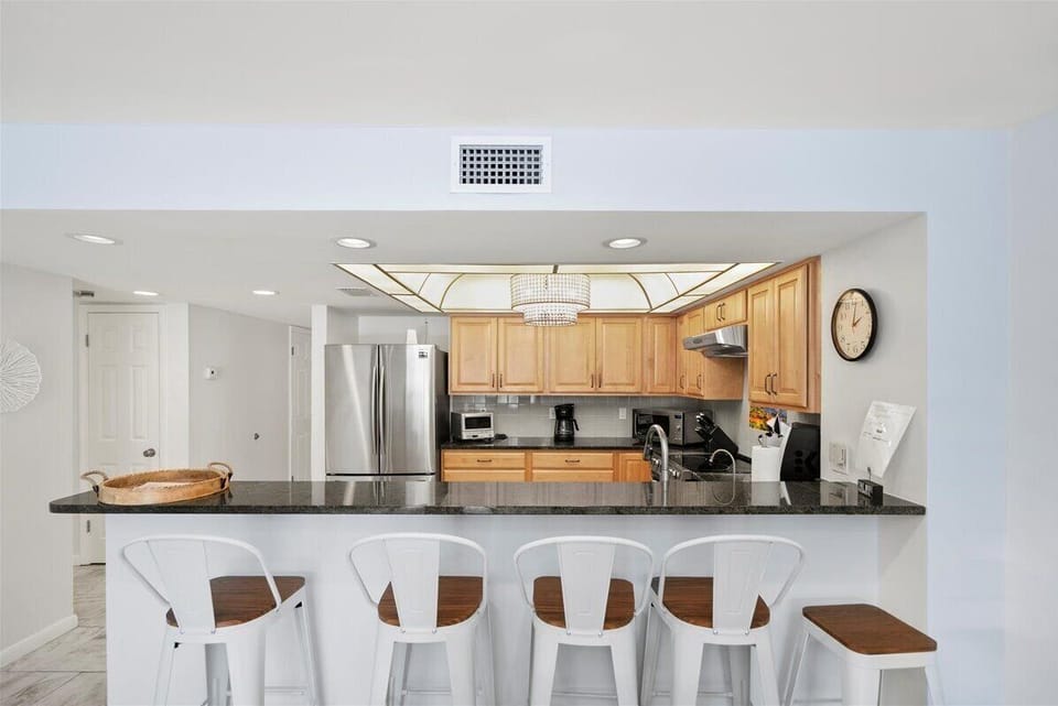 Bright and spacious kitchen featuring stainless steel appliances, granite countertops, and bar seating for easy conversations while cooking.