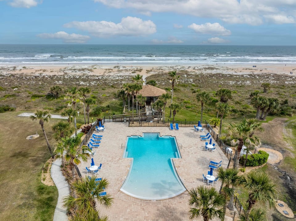 Stunning second pool area overlooking the ocean surrounded by tropical palms and resort amenities.