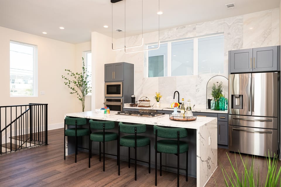Modern open-concept kitchen and dining area with designer lighting and stainless steel appliances.