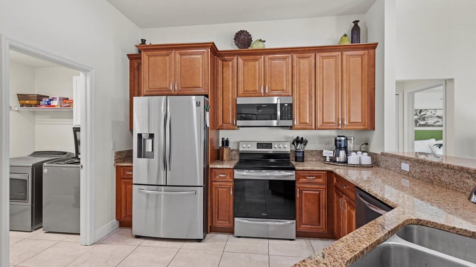 Equipped with stainless steel appliances including a french door refrigerator, electric range and stovetop, microwave, and dishwasher.