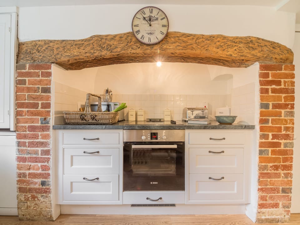 The kitchen boasts exposed beams and brickwork