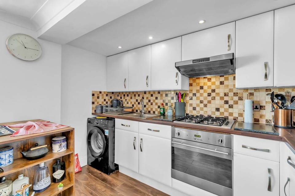 Open-plan kitchen with high-gloss cabinets, integrated appliances, and breakfast bar seating.