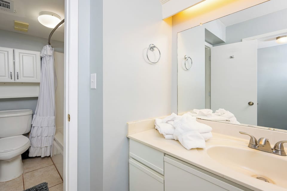Soft towels rest on the master bath counter while a shower curtain hints at refreshing showers after days outdoors