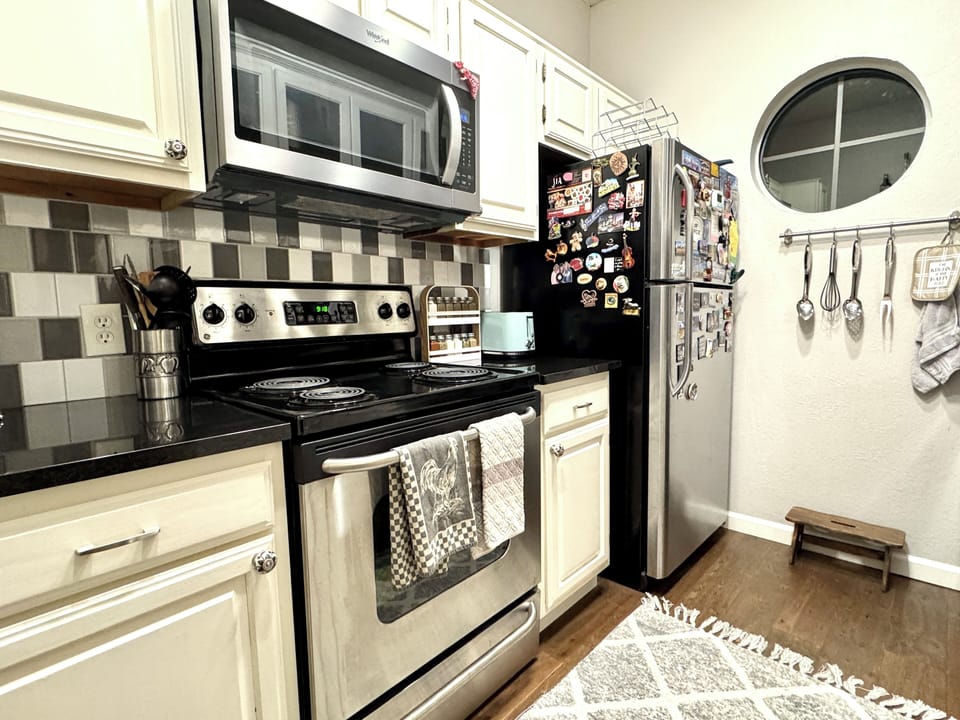 Fully equipped kitchen featuring a dishwasher, large microwave, oven, & spices. 