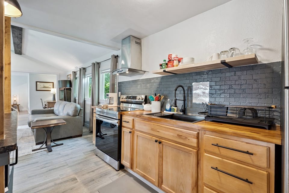 Fully stocked kitchen with solid butcher block countertops, a deep farmhouse sink, and open shelving for easy access.