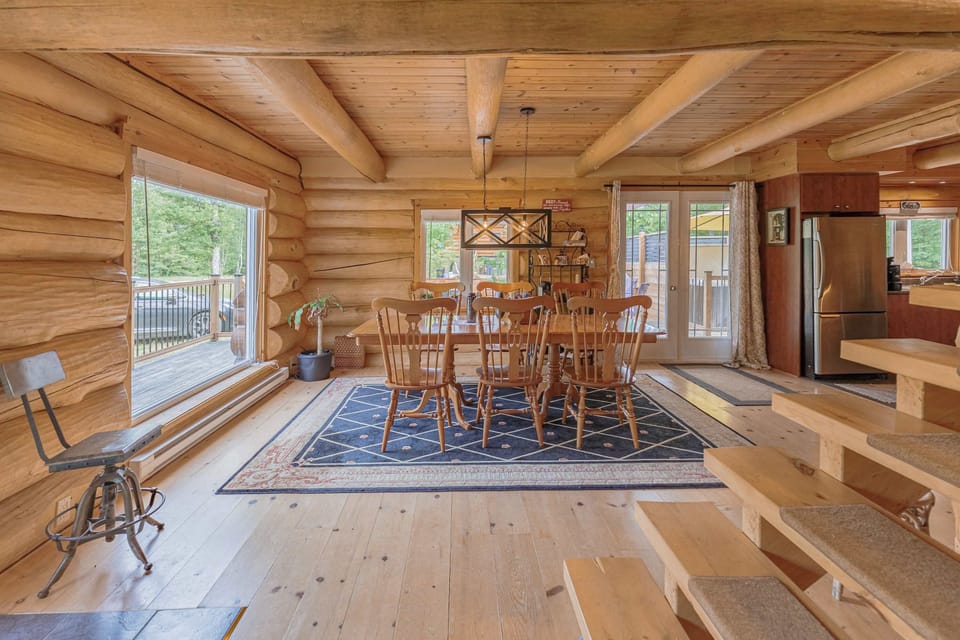 Dining space with natural light and a cozy log staircase backdrop