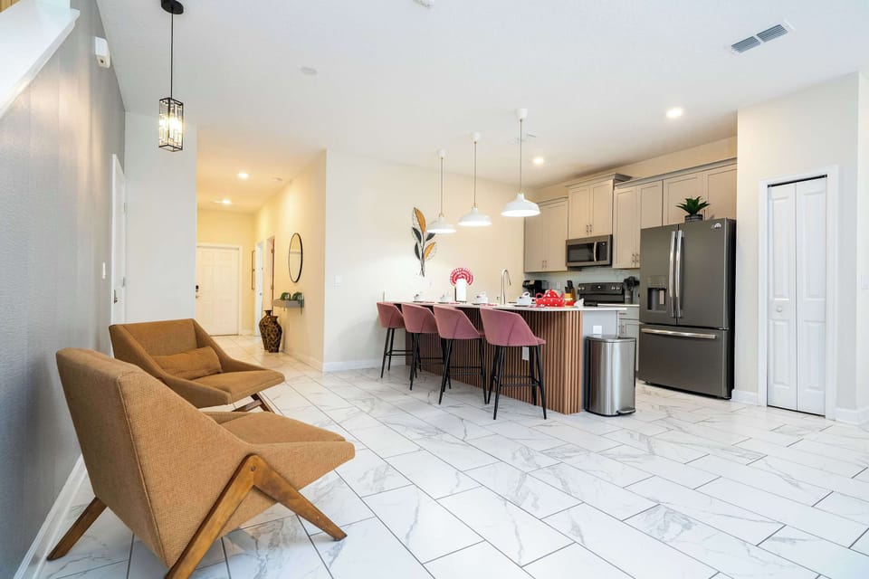 Open-concept living with marble-look floors and chic mid-century chairs. Whip up meals in the stylish kitchen and gather at the island with plush stools-bright, modern vibes from entry to lounge.
