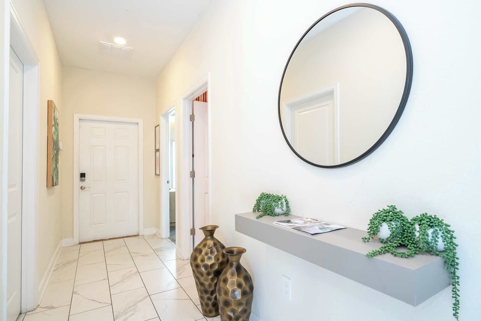 Chic entry hall with marble-look tile, floating shelf and round mirror-bright, modern welcome into your getaway.