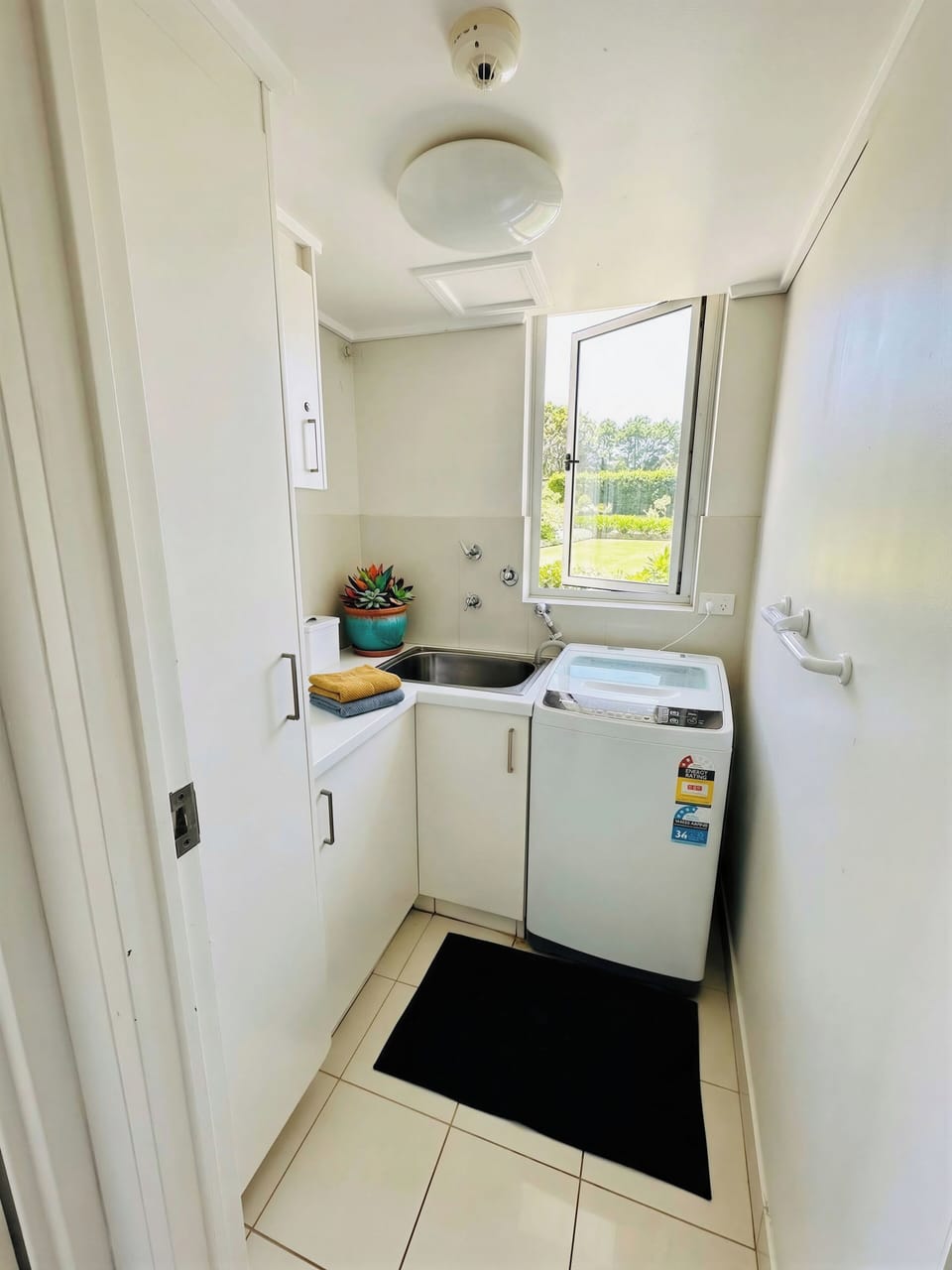 Compact laundry with washer, sink and natural light — convenient for longer stay