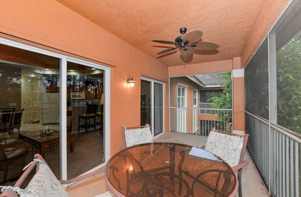 Private screened balcony with outdoor seating, ceiling fan, and covered space for relaxing outdoors.