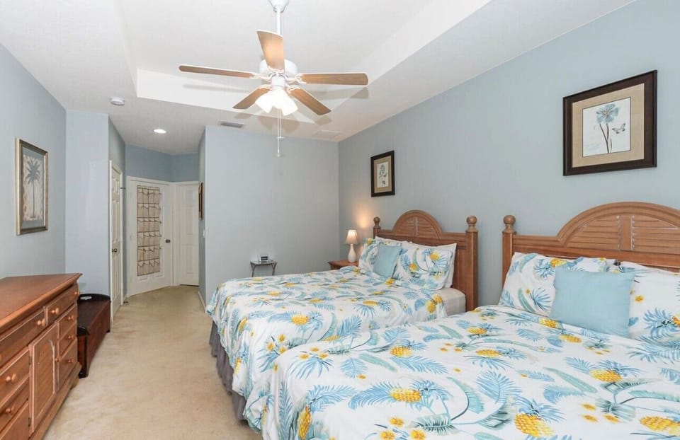 Spacious bedroom with a large bed, ceiling fan, dresser storage, and a relaxing neutral layout.